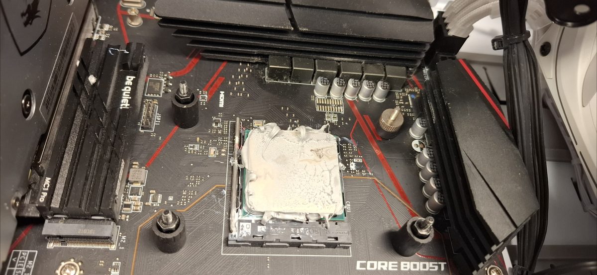 CPU mit stark überschüssiger Wärmeleitpaste, die über den Prozessorrand in den Sockel gelaufen ist